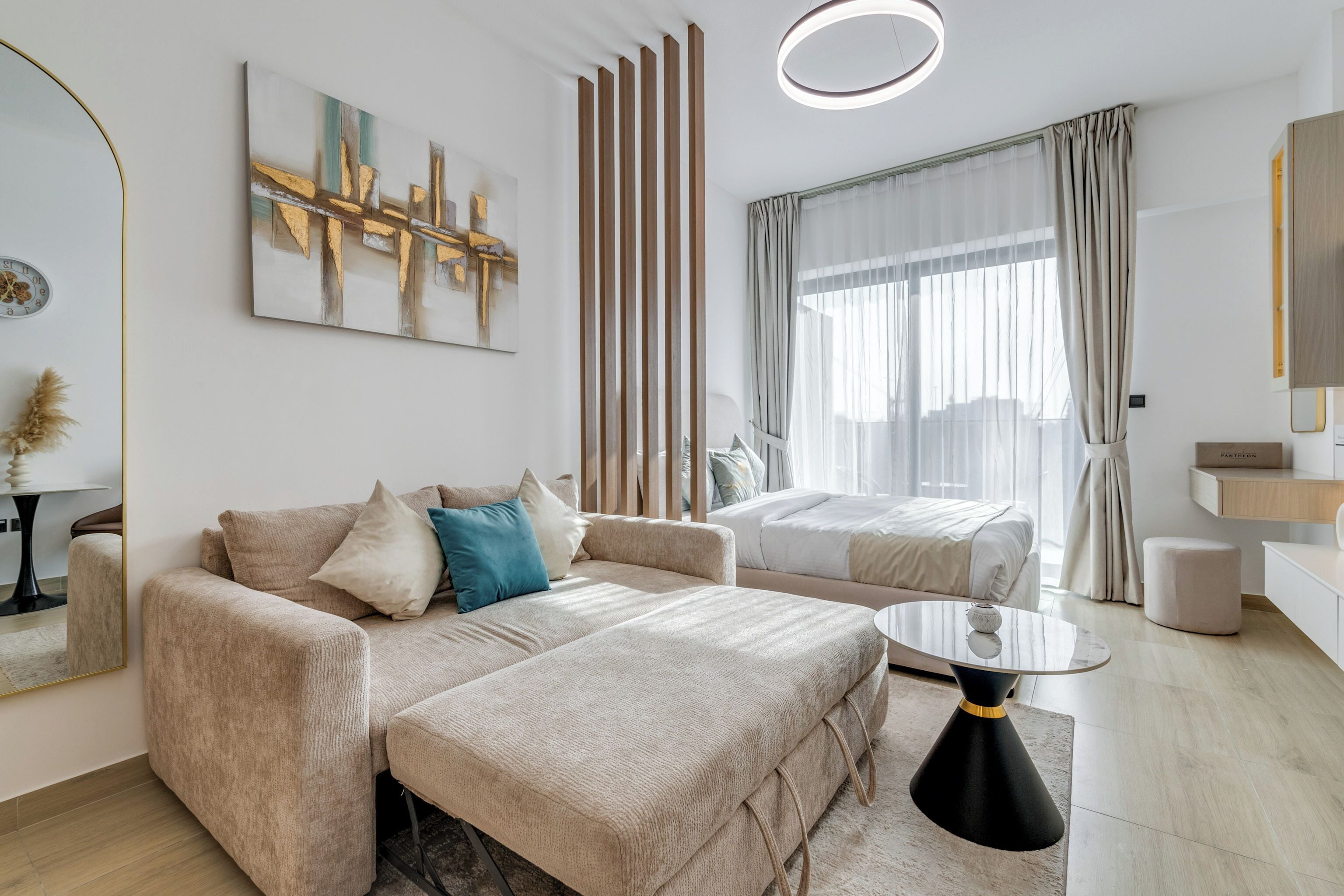 A modern living room with a beige sofa, a coffee table, and a large window with curtains.