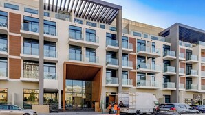 A multi-story hotel with a modern architectural design, featuring balconies with glass railings, large windows, and a central entrance with a wooden overhang.