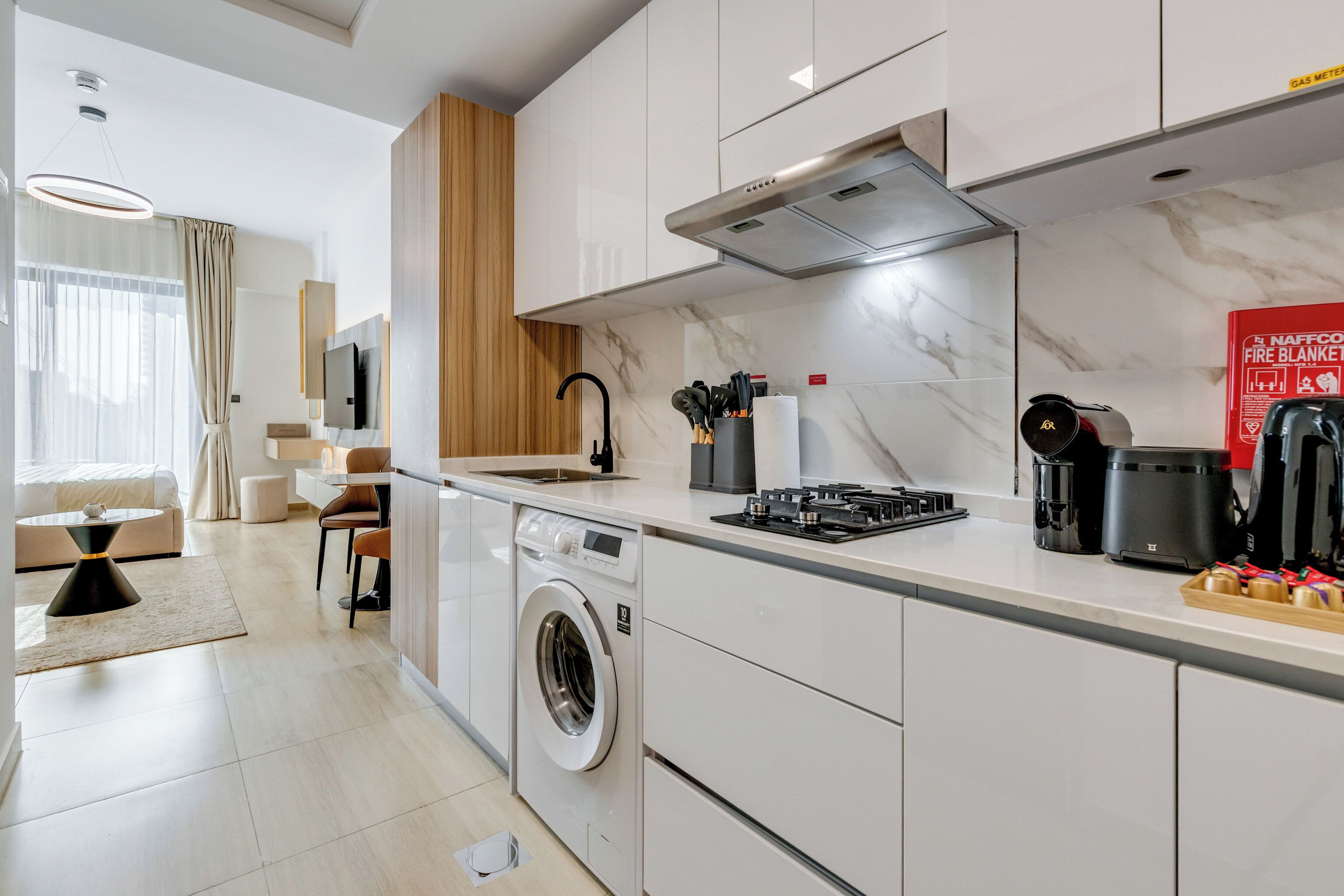 A modern kitchen with a built-in washer, a gas stove, and a coffee maker.
