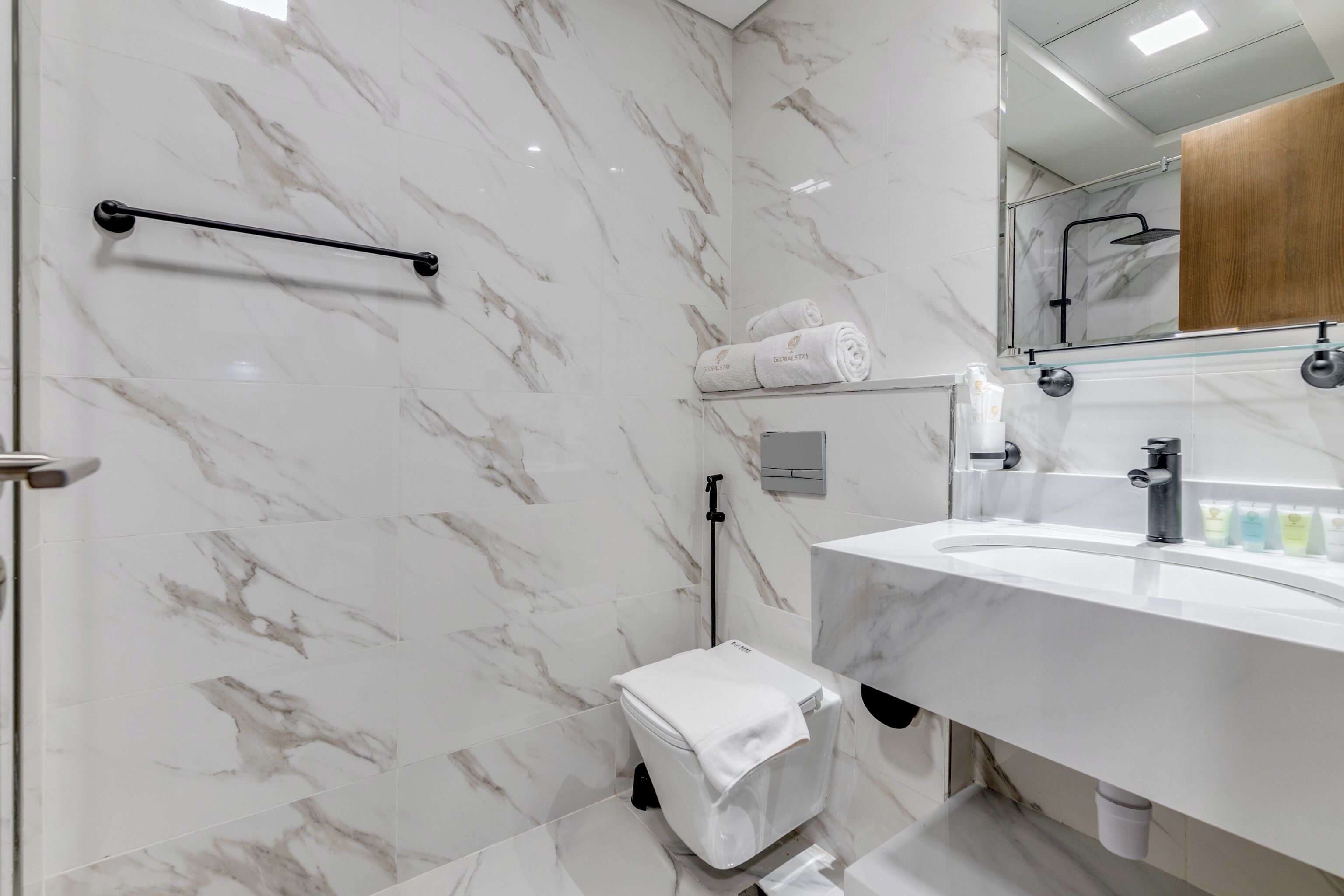 A modern bathroom with a marble backsplash, a white sink, and a glass shower enclosure.