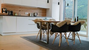 Une cuisine moderne avec des meubles blancs, un plan de travail en bois et un coin repas comprenant une table et des chaises.