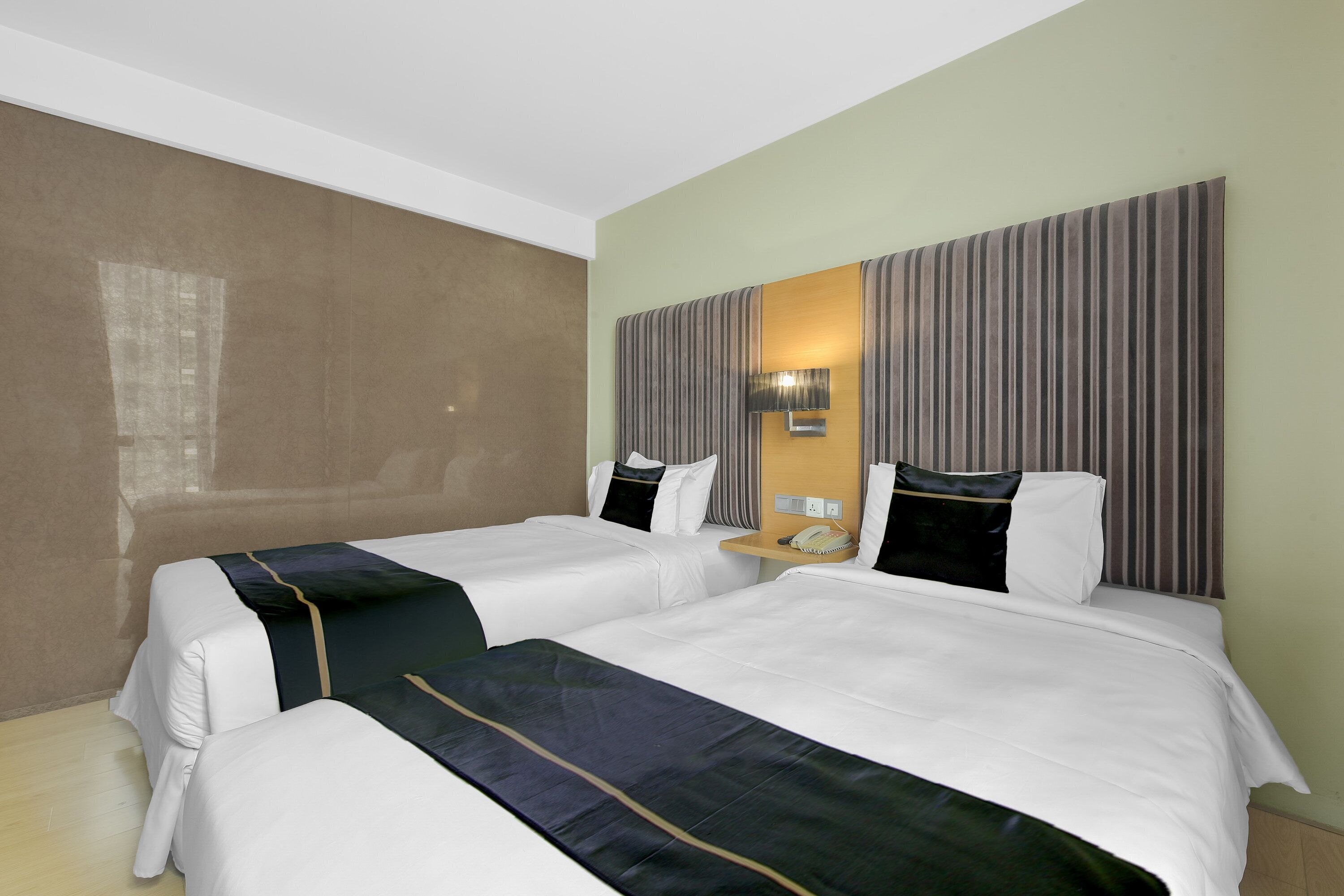 A hotel room with two beds, a large mirror, and a nightstand with a lamp.