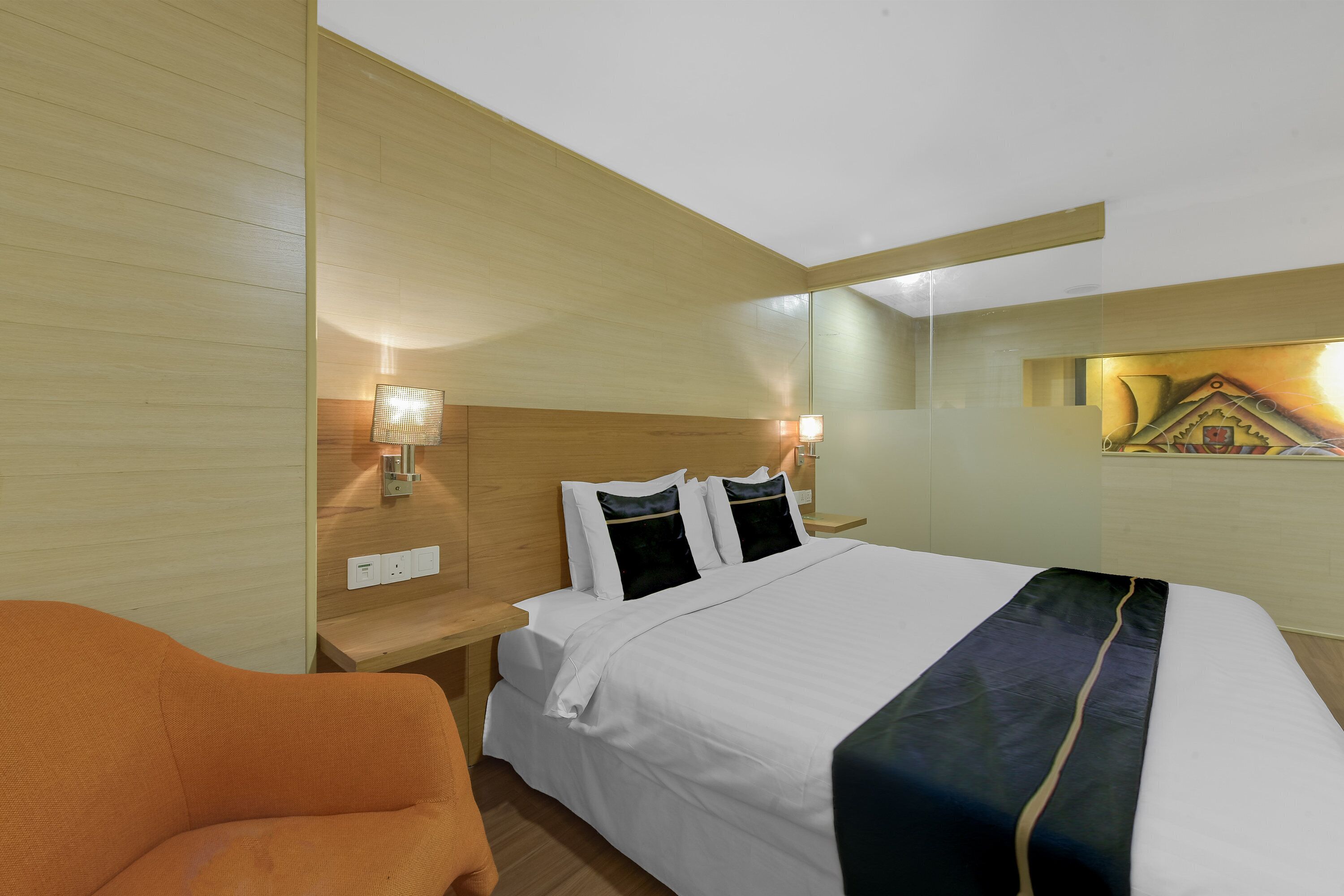 A hotel room with a bed, a nightstand, a lamp, and a chair.