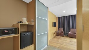 A compact hotel room with a kitchenette, a seating area with two chairs, a flat-screen TV, and a sliding door leading to a balcony. - Sunday Hotel Subang (Subang Jaya)
