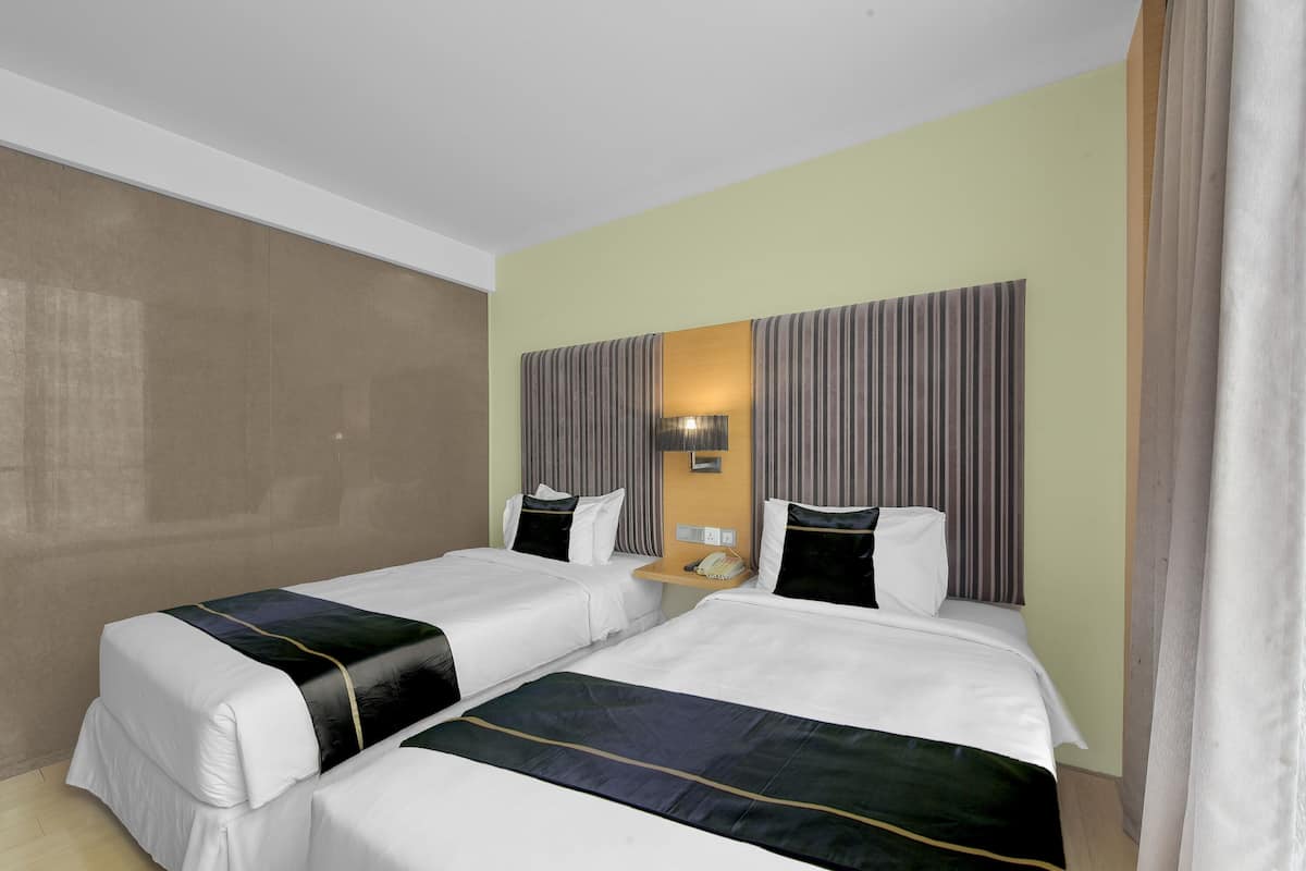 Une chambre d’hôtel avec deux lits, une table de chevet et une lampe fixée au mur.