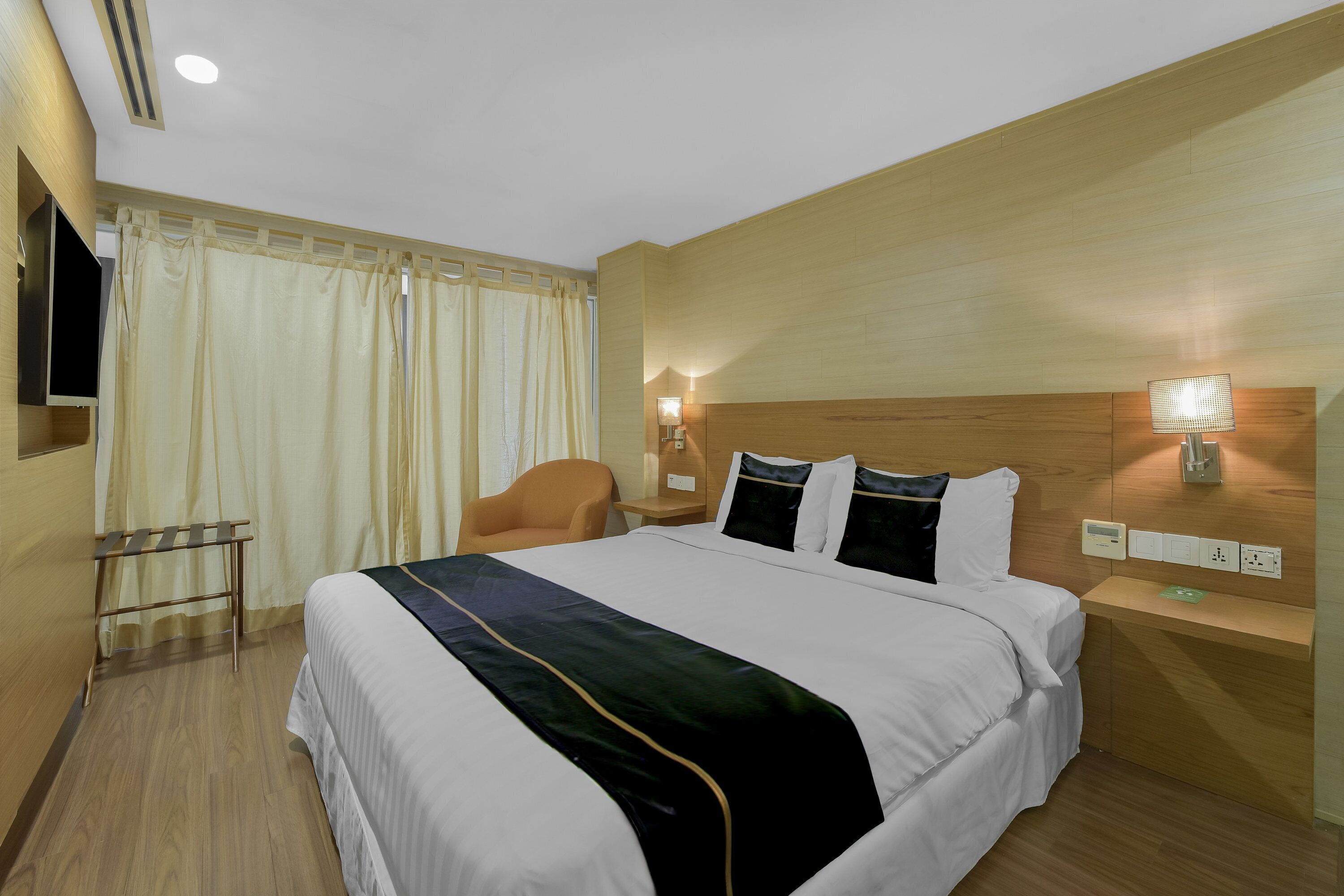 Habitación de hotel con una cama grande, un escritorio, una silla y un televisor montado en la pared.