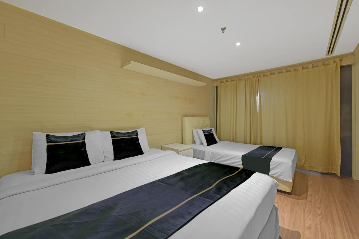 Une chambre d’hôtel avec deux lits, des têtes de lit en bois et une grande fenêtre avec des rideaux.