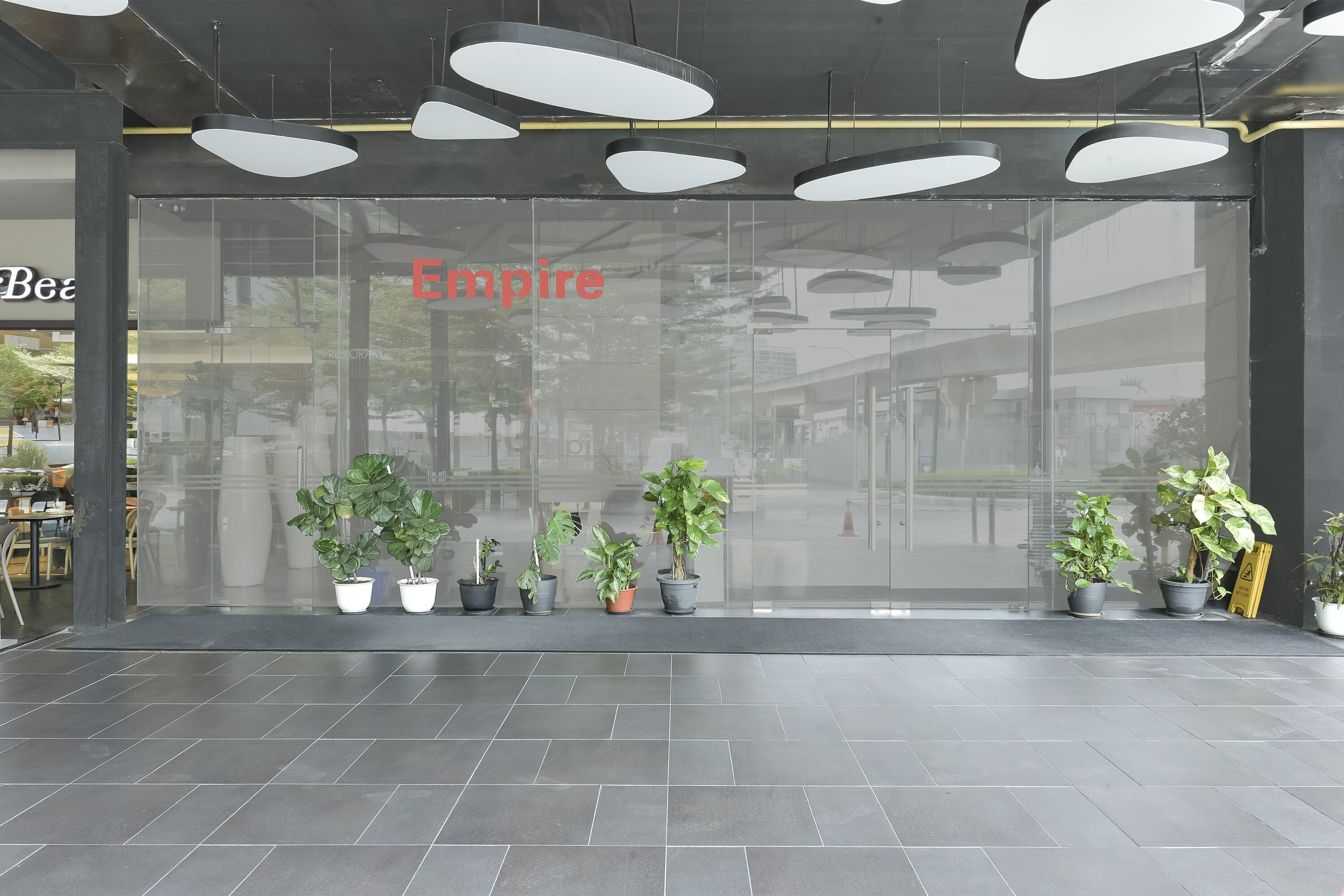 A storefront with the name "Empire" in red letters, potted plants in front, and a tiled floor.