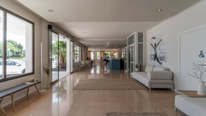 Un hall d’hôtel spacieux, doté d’un long comptoir d’accueil, d’un espace salon et de grandes fenêtres offrant une vue sur l’extérieur.