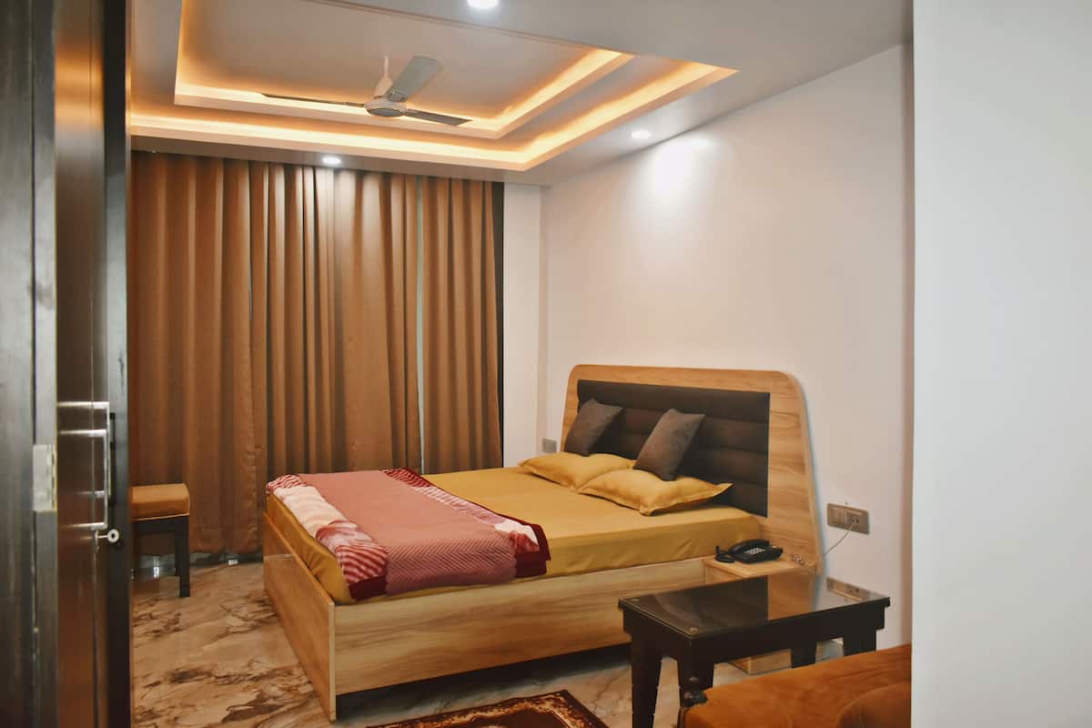 A bedroom with a wooden bed, a desk, a chair, a ceiling fan, and a window with curtains.