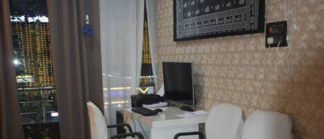 A modern office space with a desk, two chairs, a computer, and a large window with curtains.