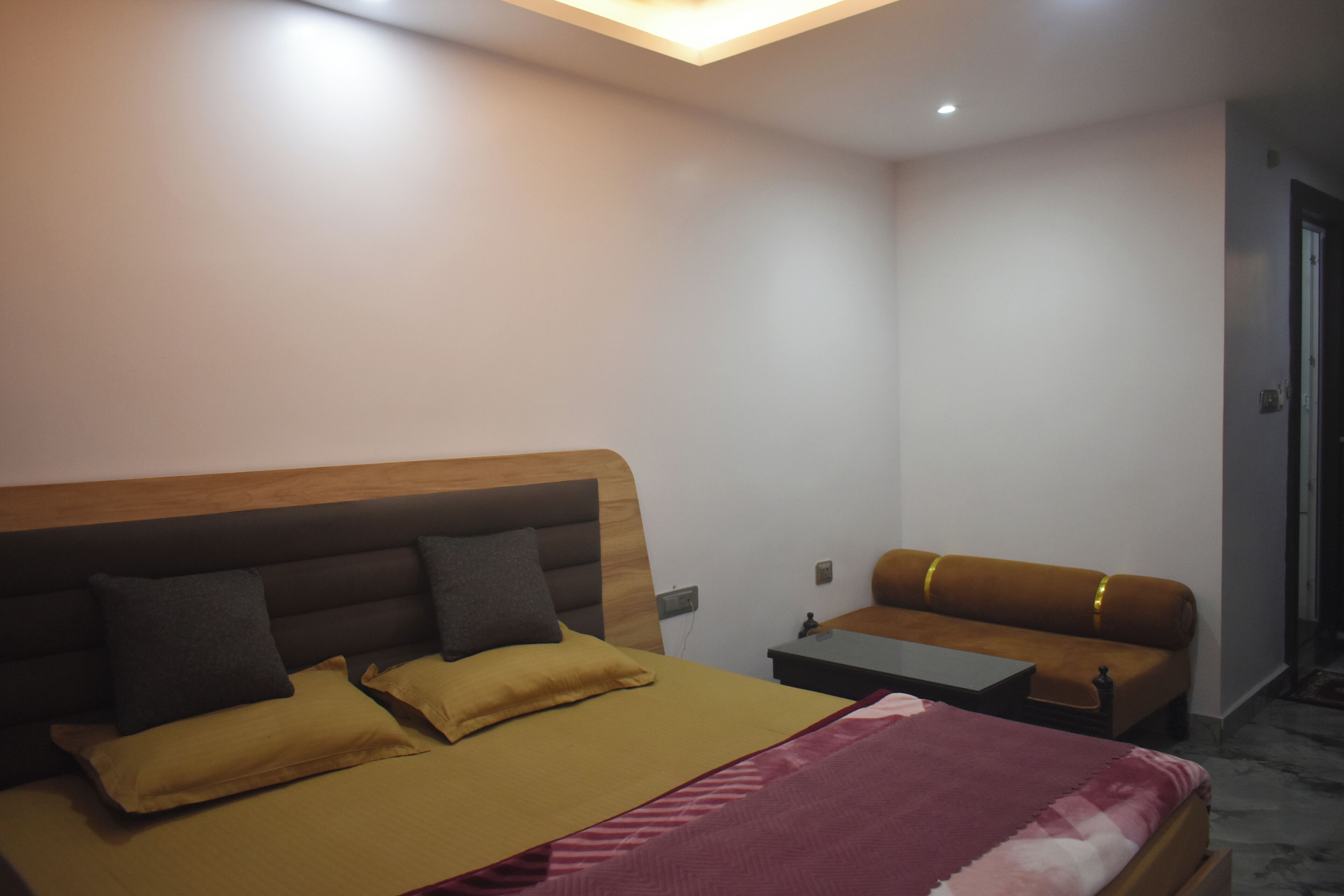 A bedroom with a bed, a sofa, a small table, and a nightstand.