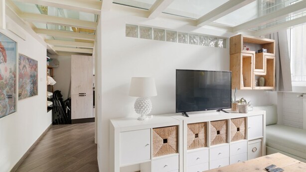 Un soggiorno moderno con una TV a schermo piatto, mobili bianchi e un tavolino in legno.