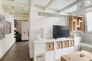 A modern living room with a flat-screen TV, white cabinetry, and a wooden coffee table.
