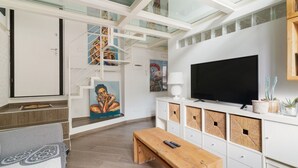 Un soggiorno moderno con una scala, un televisore a schermo piatto, una panca di legno e un quadro.