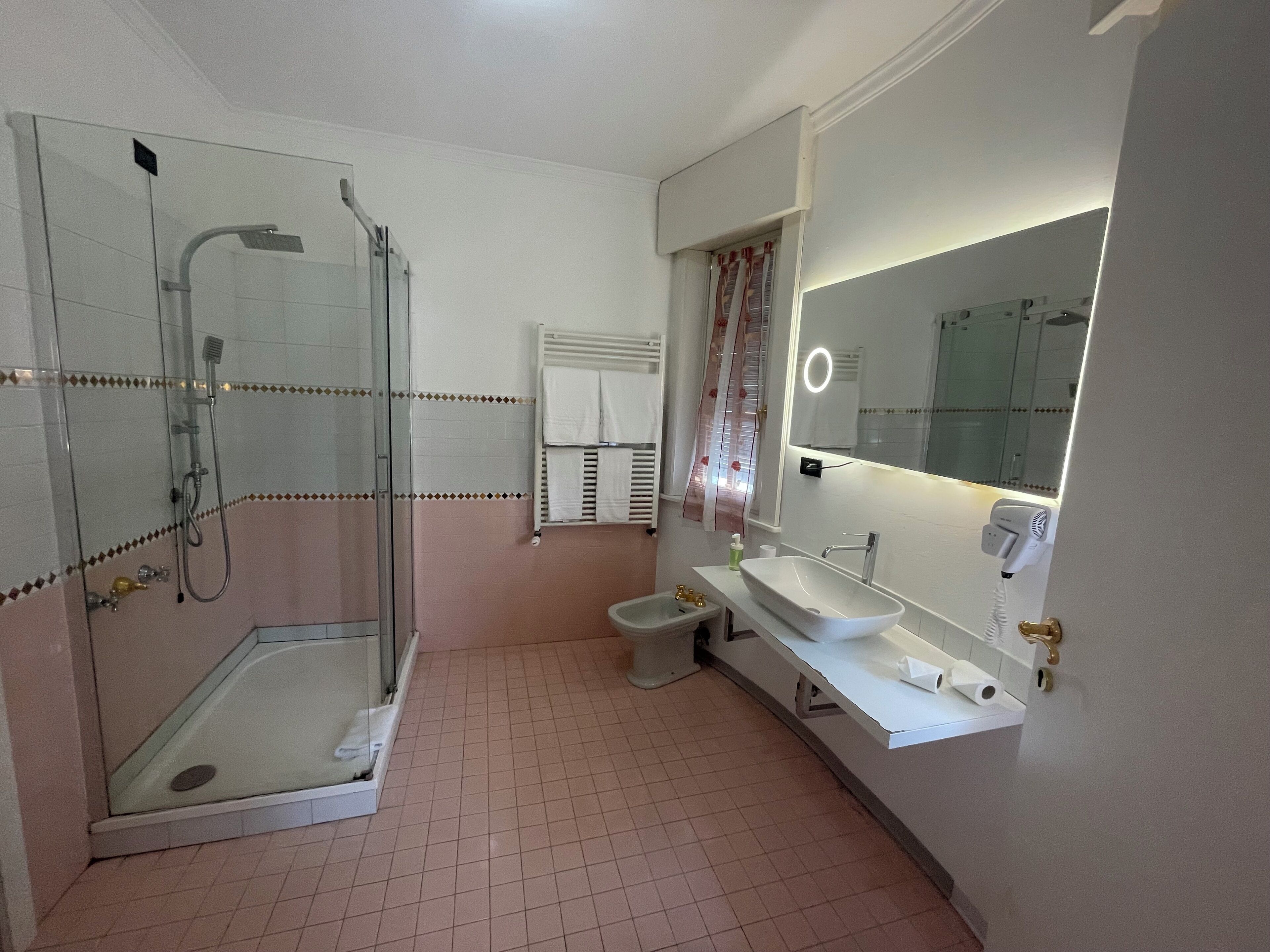 Ein Badezimmer mit Duschkabine, Waschbecken, Spiegel und Toilette.
