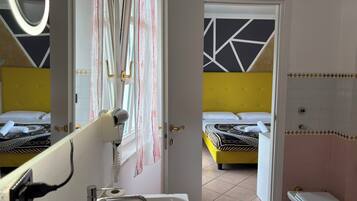 Ein Hotelzimmer mit zwei Betten, einem Badezimmer und einem Spiegel, der den Raum reflektiert.