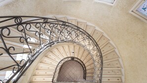 Una escalera de metal curva con barandillas ornamentales que conduce a un arco de entrada.