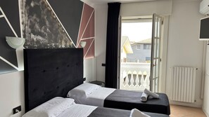 Habitación de hotel con dos camas, un ventanal grande, un radiador y vistas al exterior.
