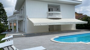 Una casa moderna de dos pisos con un porche cubierto y una piscina.