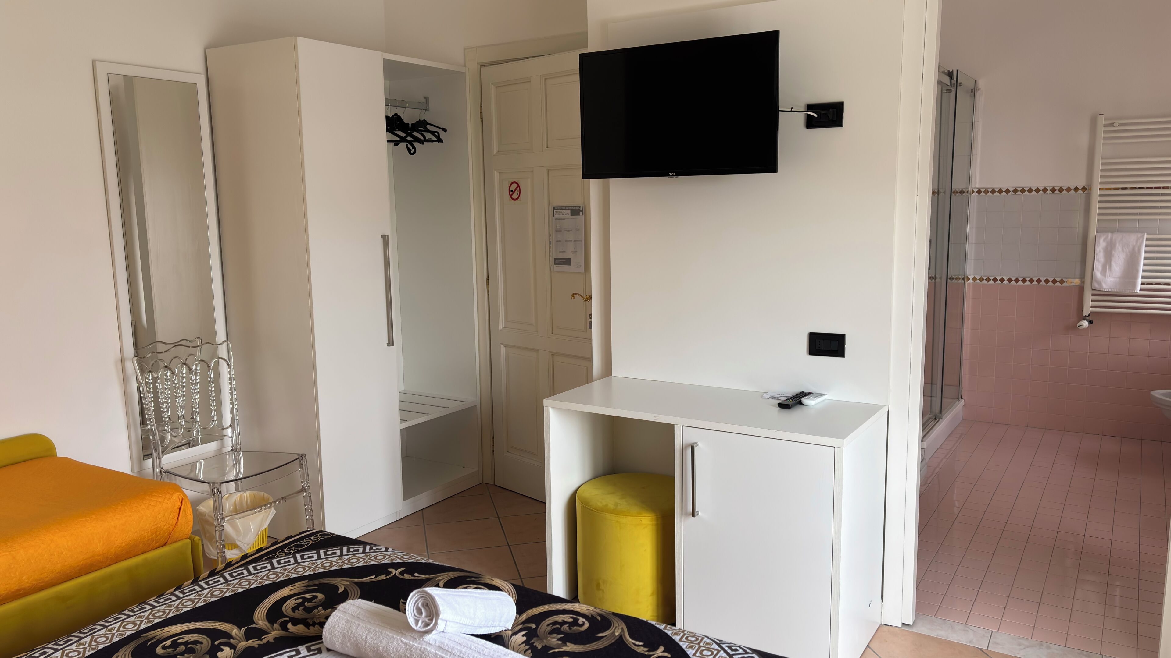Ein Hotelzimmer mit Bett, Schreibtisch, Fernseher, Kleiderschrank und Dusche.