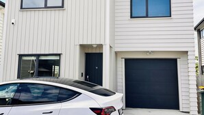 Et moderne toetagers hus med hvide facader, en garage og en hvid bil foran.