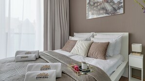 A hotel room with a bed, pillows, a tray with a cup and snacks, and a painting on the wall. - Kwartał Kamienic by Downtown Apartments (Gdańsk)