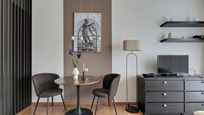 A modern living room with a round table, two chairs, a television, and a cabinet. - Kwartał Kamienic by Downtown Apartments (Gdańsk)