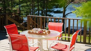 A deck with a round table and four chairs, overlooking a body of water.