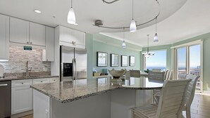 Una cocina moderna con encimeras de granito, muebles blancos y una isla central.
