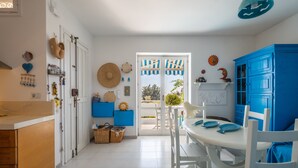 A kitchen with white cabinets, a blue dining area, and a view through the door. - Sea View Terrace - Santa Caterina di Nardò (Nardò)