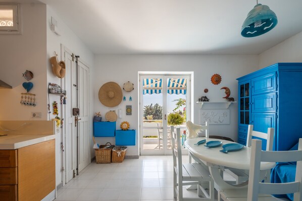 A kitchen with white cabinets, a blue dining area, and a view through the door.