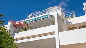 A white building with a balcony, a blue and white awning, and pink flowers. - Sea View Terrace - Santa Caterina di Nardò (Nardò)