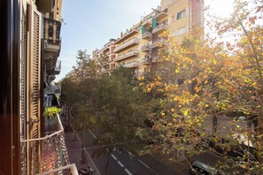 A multi-story residential building with balconies, a street below, and trees with autumn leaves. - Fabulous 2-Bedroom Apartment Eixample (Barcelona)
