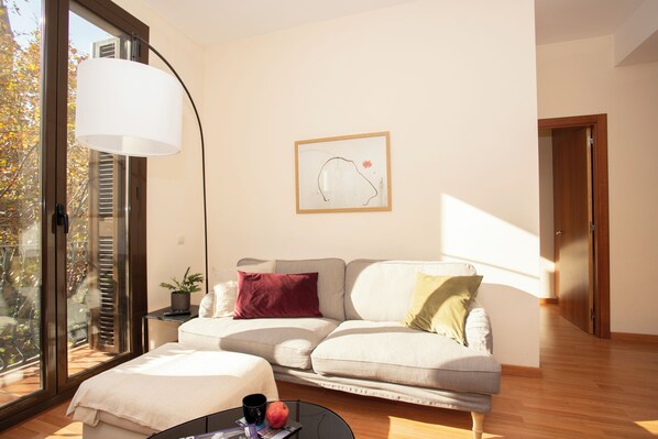 A modern living room with a sofa, a coffee table, and a floor lamp. - Fabulous 2-Bedroom Apartment Eixample (Barcelona)