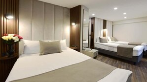 Moderni hotellihuone, jossa on suuri sänky, yöpöytä, peili ja pieni oleskelualue, jossa on sohva.