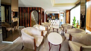 A spacious lobby with leather armchairs, a central round table, and a bar area in the background. - Hotel Öncü (İstanbul)