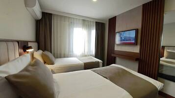 Een hotelkamer met twee bedden, een aan de muur bevestigde televisie en een airconditioning.