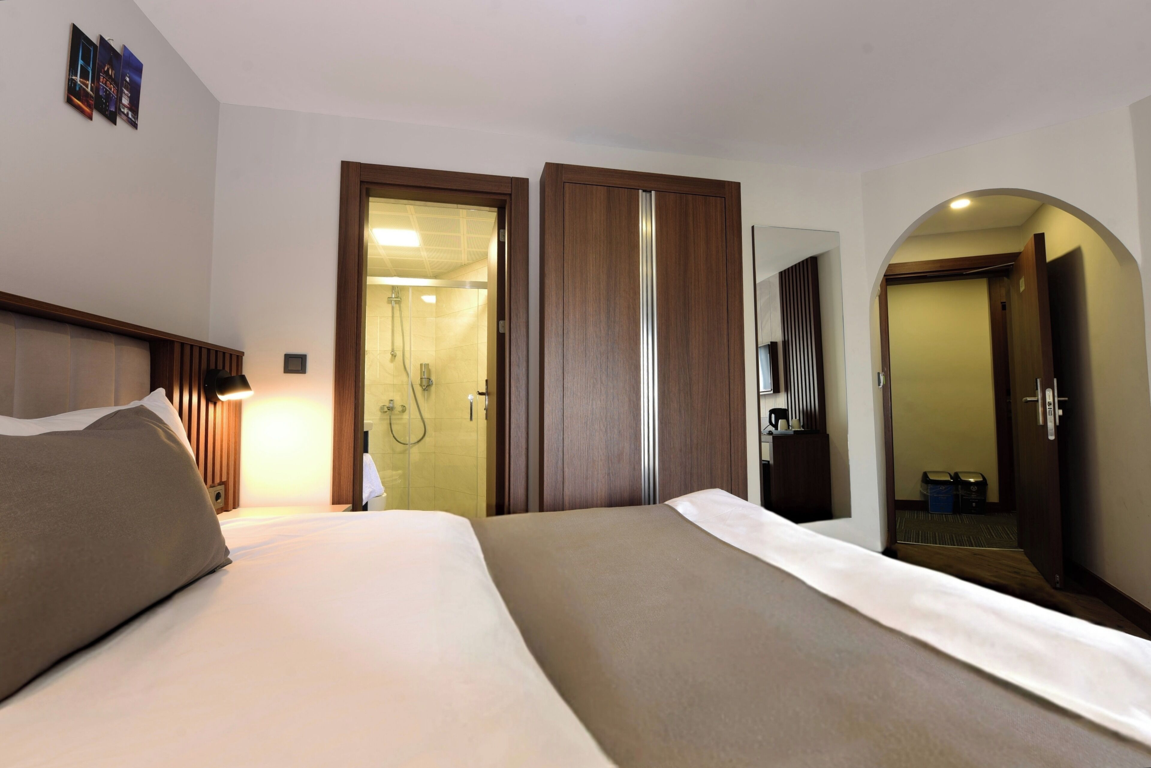 Una habitación de hotel con cama, zona de ducha y espejo.