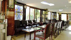 A hotel lobby with a long reception desk, multiple seating areas with chairs and tables, and large windows offering views of the outdoors. - Hotel Öncü (İstanbul)