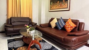 Ein Wohnzimmer mit zwei braunen Ledersofas, einem Glastisch und einem gemusterten Teppich.