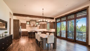 Cucina spaziosa con un'isola grande, pavimento in legno e vista panoramica tramite ampie porte scorrevoli in vetro.