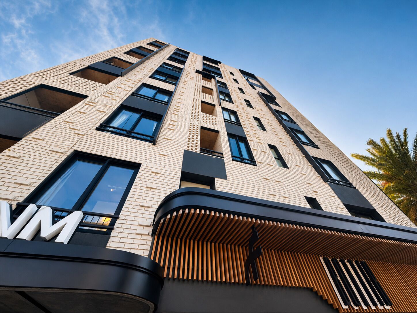 A high-rise building with a modern architectural design, featuring a prominent 'VM' sign on the facade.