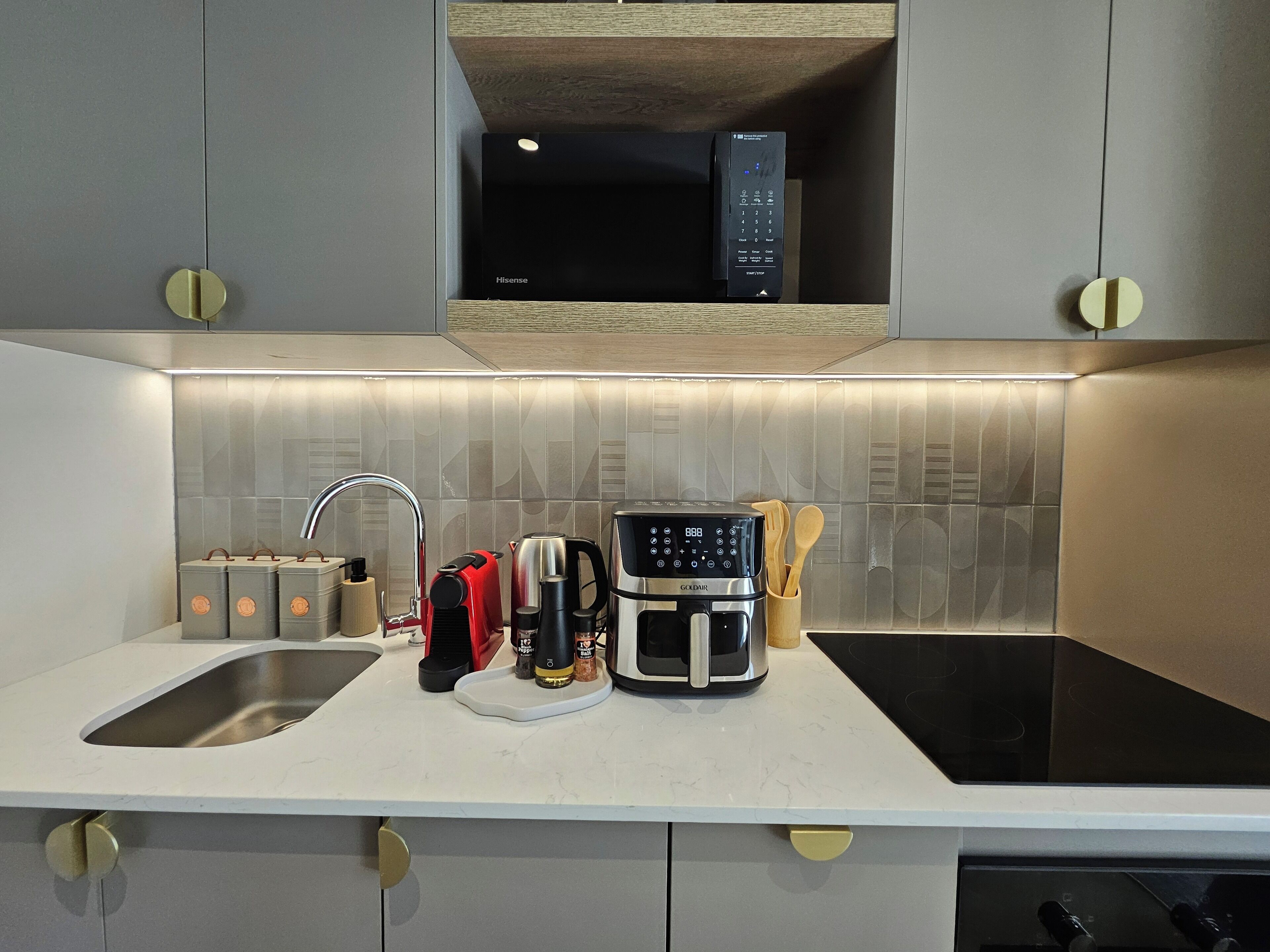 A modern kitchen with a built-in microwave, a coffee maker, and a kettle on the countertop.
