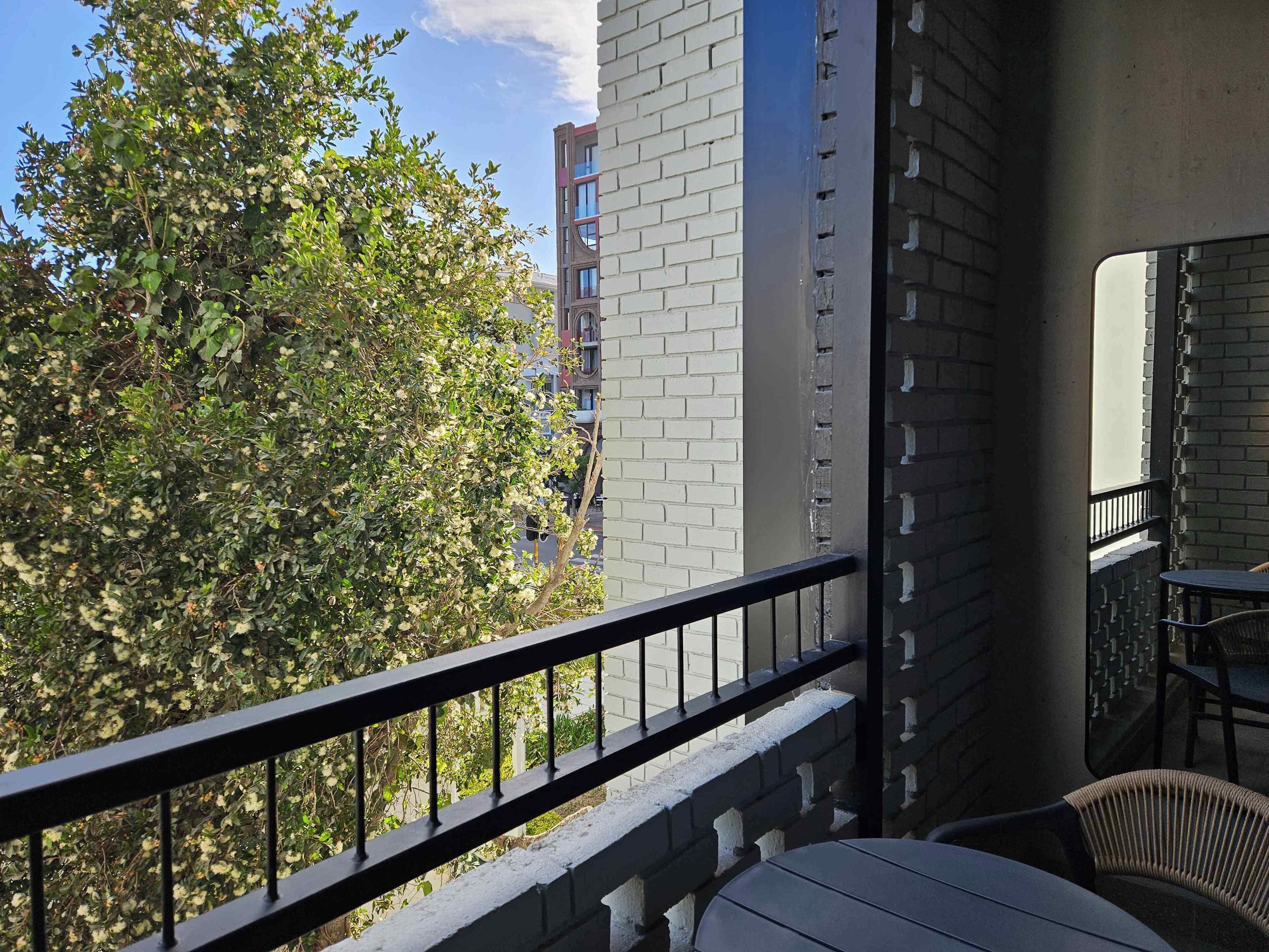Ein Balkon mit Blick auf einen Baum und ein Gebäude.
