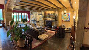 A spacious living room with a fireplace, a television, and a bookshelf. - Royal Suite (Mungia)