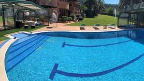 A swimming pool with a curved design, surrounded by lounge chairs and a covered seating area. - Royal Suite (Mungia)
