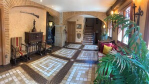 A hallway with a tiled floor, a staircase, and a large plant. - Royal Suite (Mungia)