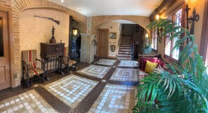 A hallway with a tiled floor, a staircase, and a large plant. - Royal Suite (Mungia)