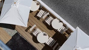 A top-down view of a deck with white round tables and chairs, arranged in a linear fashion.